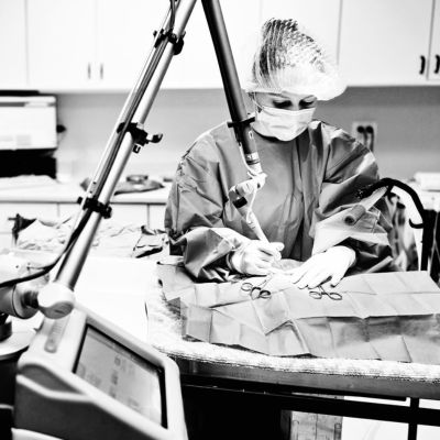 A person in scrubs is focused on a task at a table with equipment